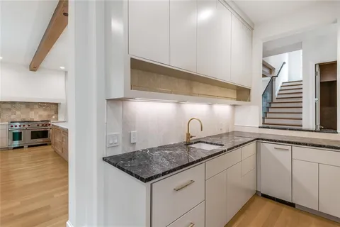 a kitchen with a sink dishwasher a stove and cabinets with wooden floor