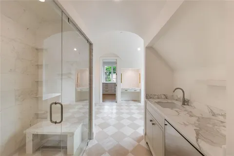 a bathroom with a granite countertop sink two mirror and shower
