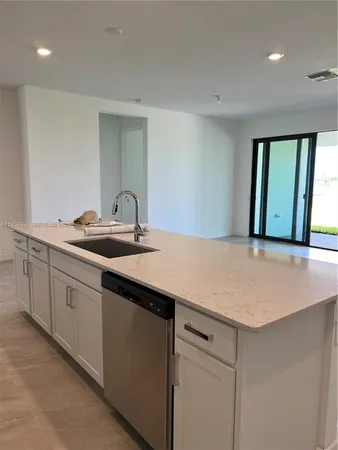 a kitchen with kitchen island a refrigerator and a sink