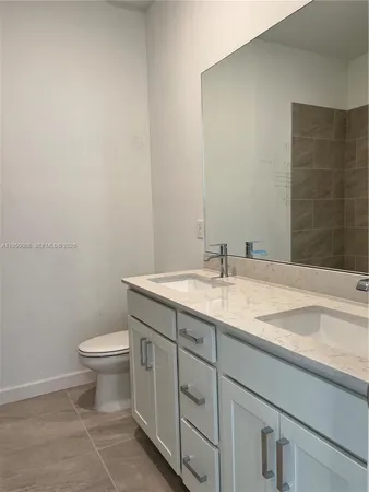 a bathroom with a granite countertop sink a toilet and a mirror