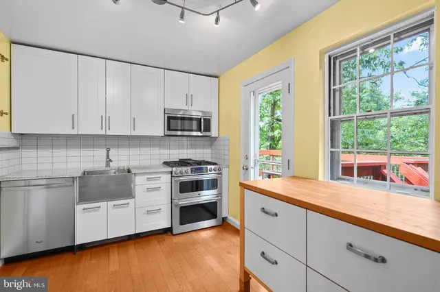 a kitchen with stainless steel appliances white cabinets a stove a sink and a microwave