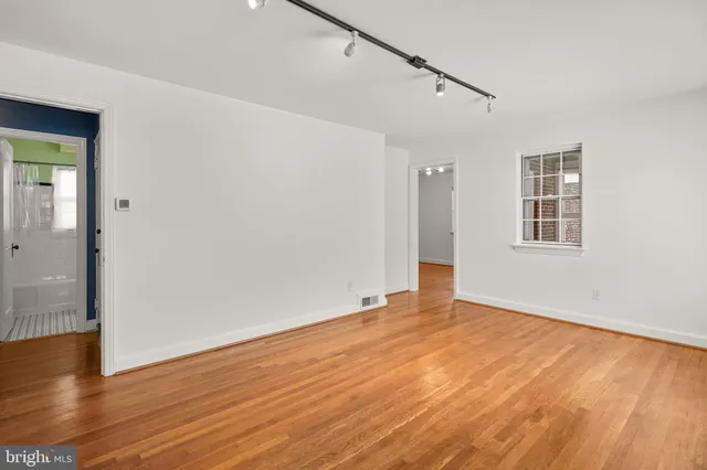 a view of an empty room with wooden floor and a window