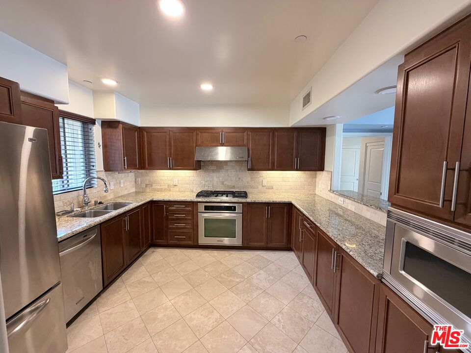 8238 West Manchester Avenue, Unit 308 Playa del Rey, CA 90293 - Photo 5 of 19 a large kitchen with granite countertop stainless steel appliances cabinets a sink and a counter top space