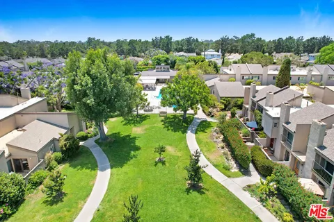 an aerial view of residential houses with outdoor space and trees