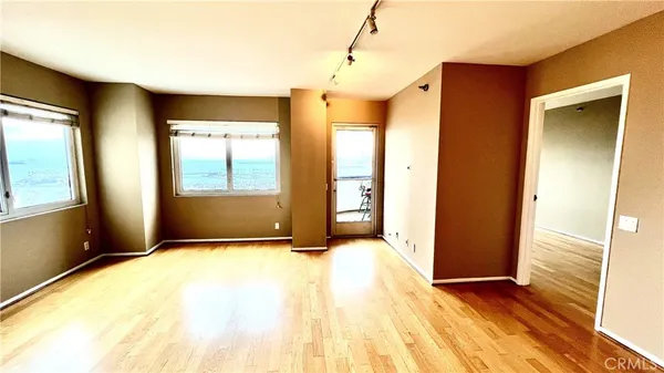 a view of an empty room with window and wooden floor