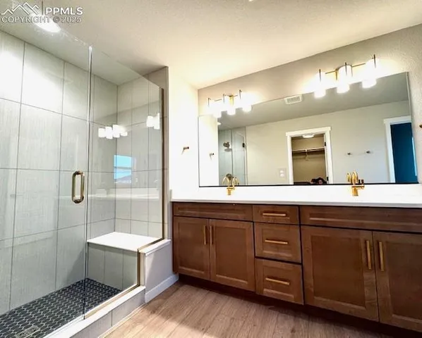 a spacious bathroom with a double vanity sink a large mirror and a shower