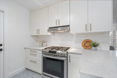 a kitchen with granite countertop white cabinets and stainless steel appliances