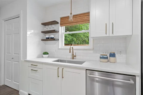 a kitchen with stainless steel appliances white cabinets and a window