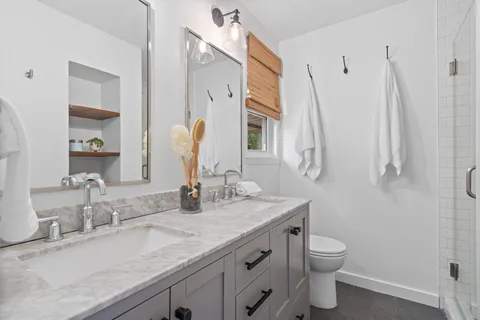 a bathroom with a granite countertop sink a toilet and a mirror