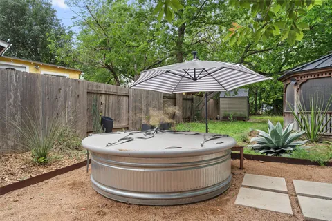 a view of a backyard with table and chairs under an umbrella with wooden fence