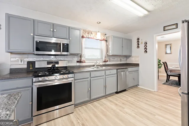 a kitchen with stainless steel appliances granite countertop a stove top oven a sink dishwasher and white cabinets