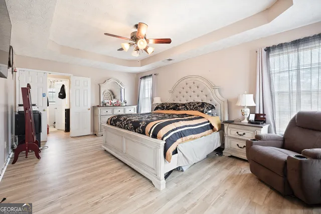 a spacious bedroom with a bed couch chandelier and a window
