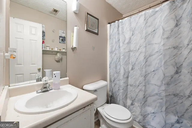 a bathroom with a sink a toilet and shower curtain