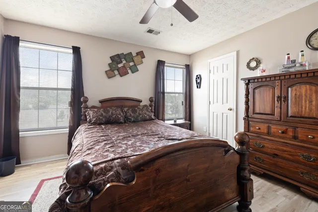 a bedroom with a bed next to a window with a flat tv screen on dresser