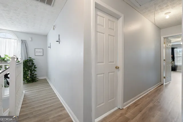 a view of a hallway with wooden floor and a bathroom