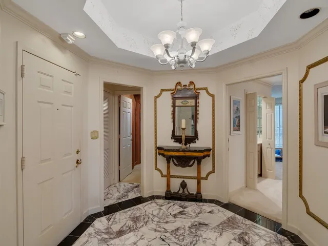 a view of a hallway with wooden floor and a chandelier