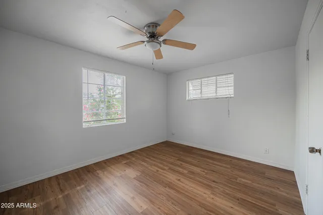 an empty room with ceiling fan and windows