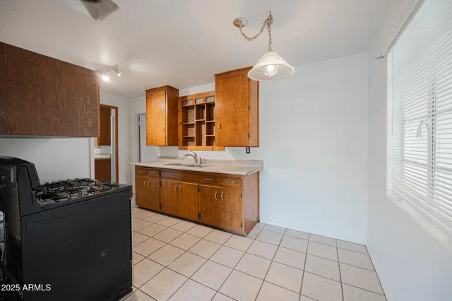 a kitchen with stainless steel appliances granite countertop a sink a stove a refrigerator cabinets and a dining table