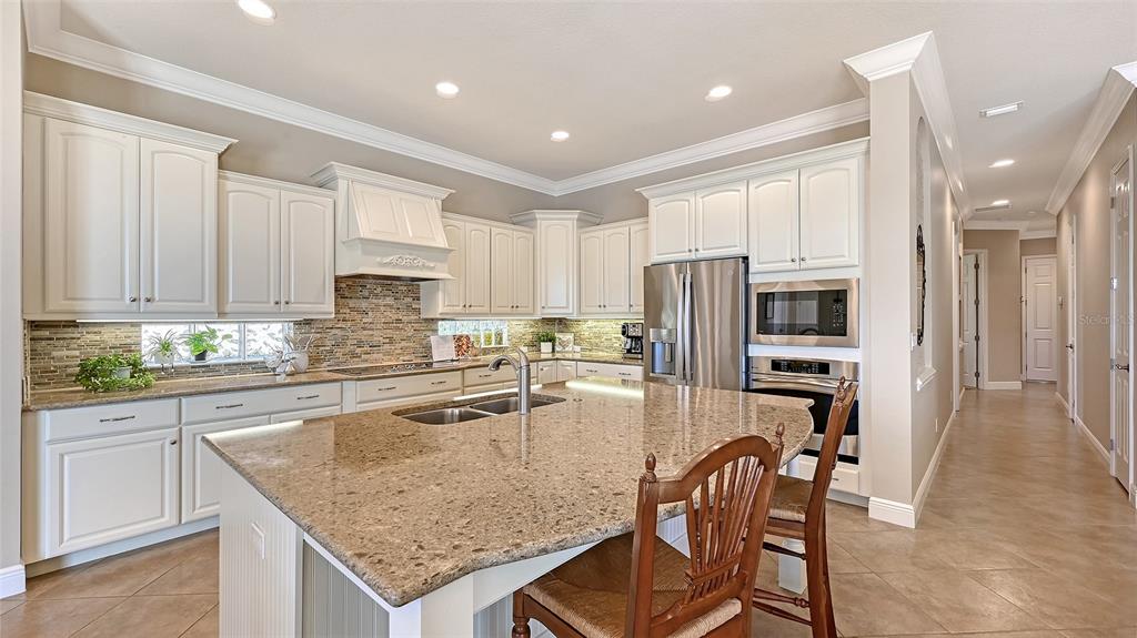 14718 Secret Harbor Place Lakewood Ranch, FL 34202 - Photo 22 of 73 a kitchen with stainless steel appliances granite countertop a stove top oven a sink refrigerator and white cabinets