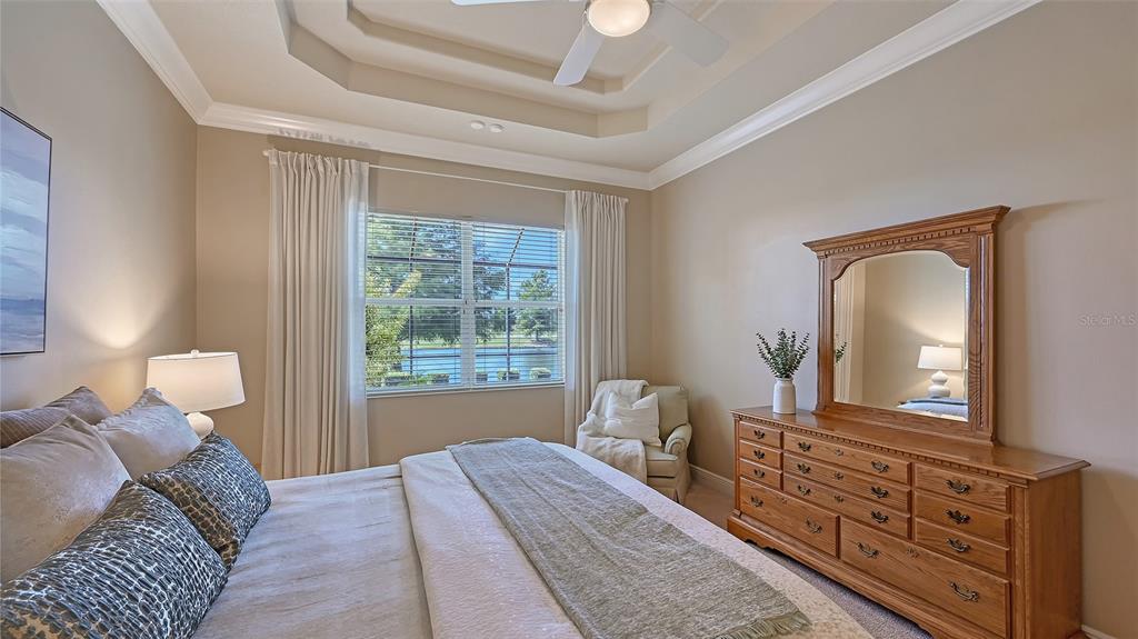 14718 Secret Harbor Place Lakewood Ranch, FL 34202 - Photo 27 of 73 a bedroom with a large bed and dresser with mirror