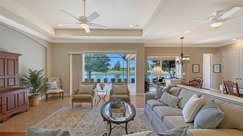 14718 Secret Harbor Place Lakewood Ranch, FL 34202 - Photo 40 of 73 a living room with furniture a chandelier fan and a large window