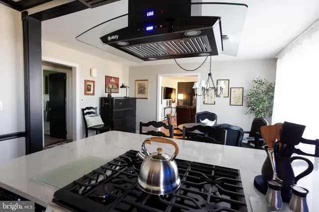 a kitchen with stainless steel appliances granite countertop a stove a refrigerator a sink a dining table and chairs with wooden floor