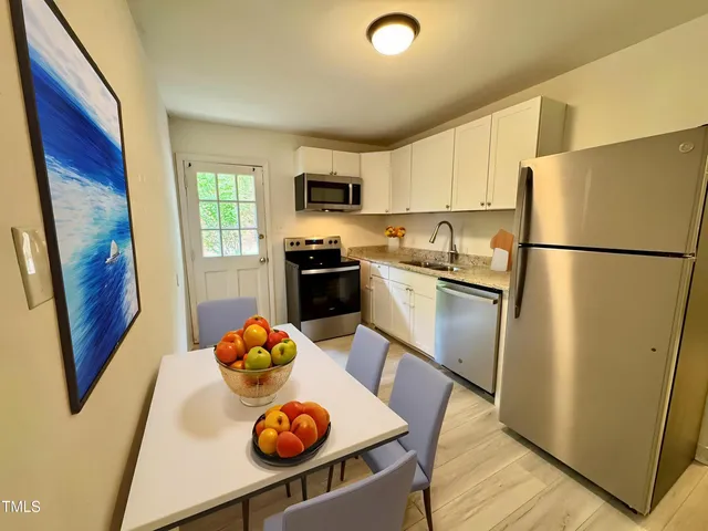 a kitchen with stainless steel appliances a refrigerator a sink a stove a microwave a dining table and chairs