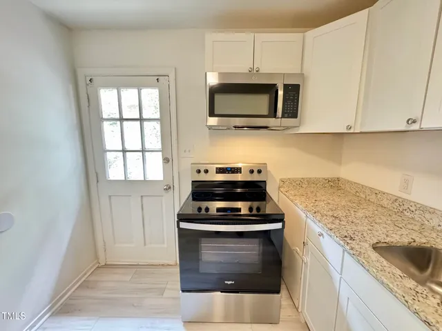 a kitchen with white cabinets and appliances