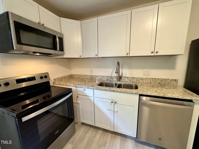 a kitchen with granite countertop cabinets stainless steel appliances and wooden floor