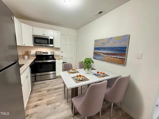 a kitchen with stainless steel appliances granite countertop a stove a microwave a dining table and chairs