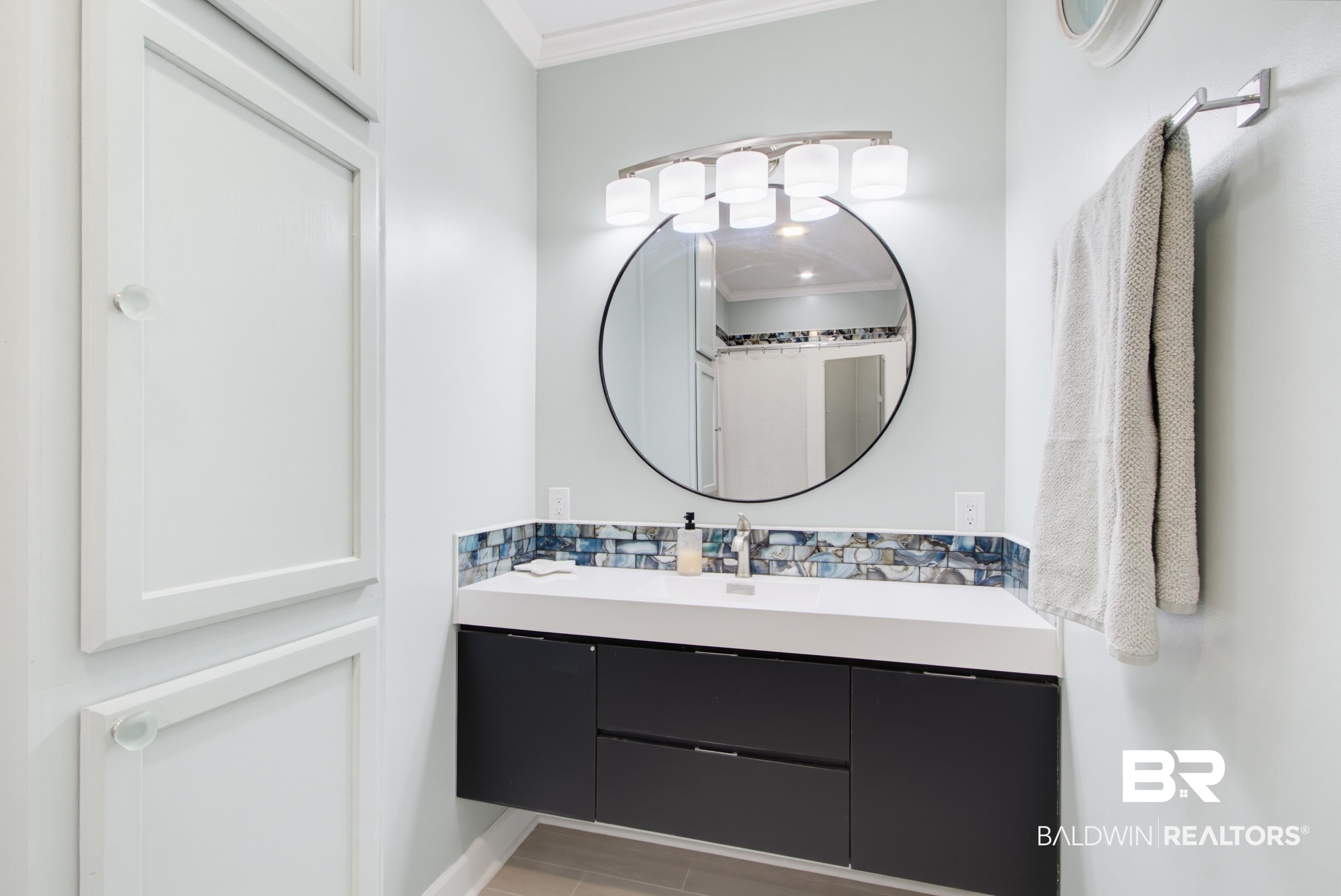 7472 Coopers Landing Road Foley, AL 36535 - Photo 23 of 40 Contemporary floating vanity with integrated sink, modern backsplash tiling, and wall-mounted storage cabinetry