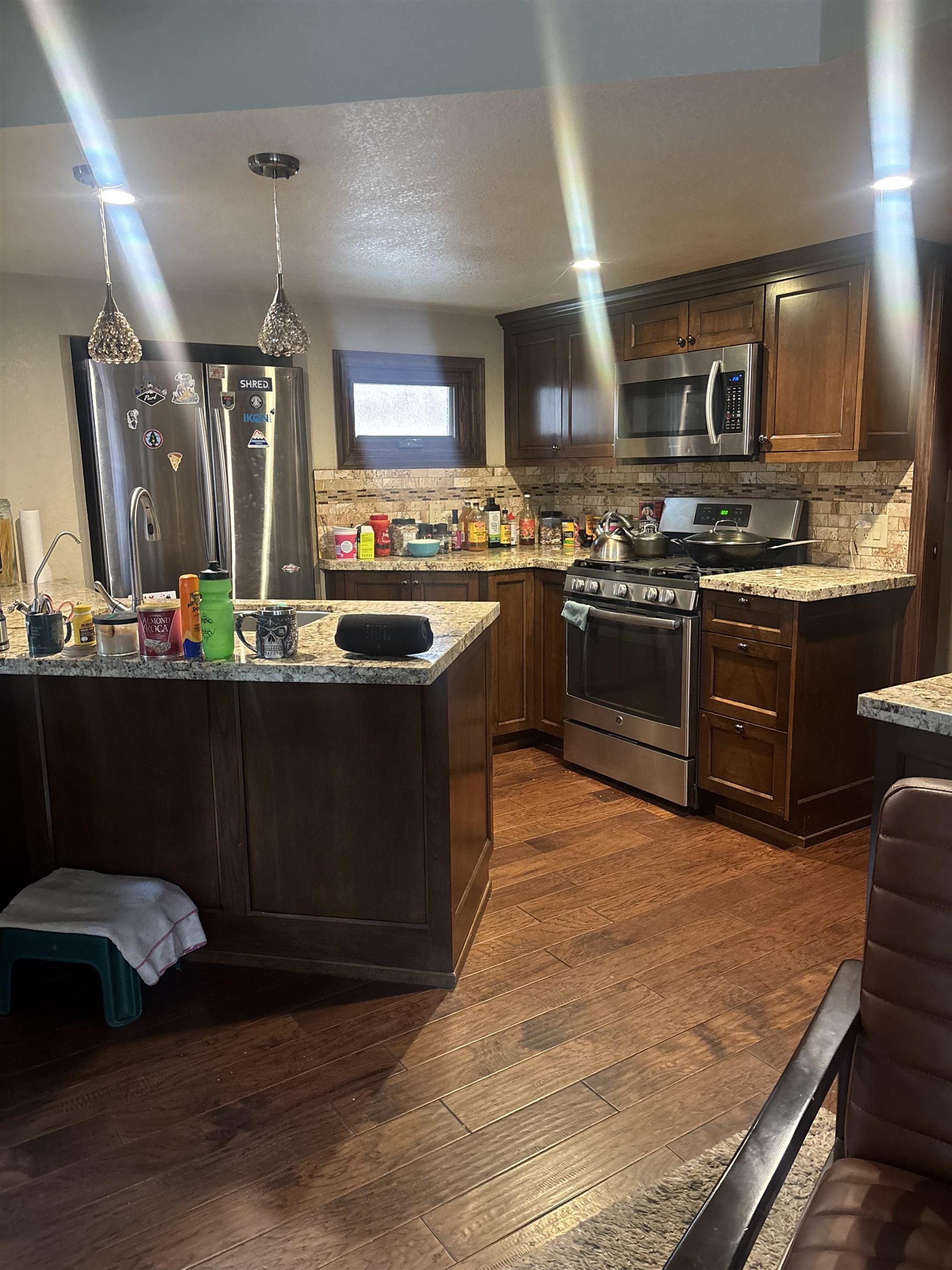 129 Sunny Slopes Road Mammoth Lakes, CA 93546 - Photo 6 of 16 Kitchen featuring stainless steel appliances, dark wood-style flooring, decorative backsplash, and light stone countertops