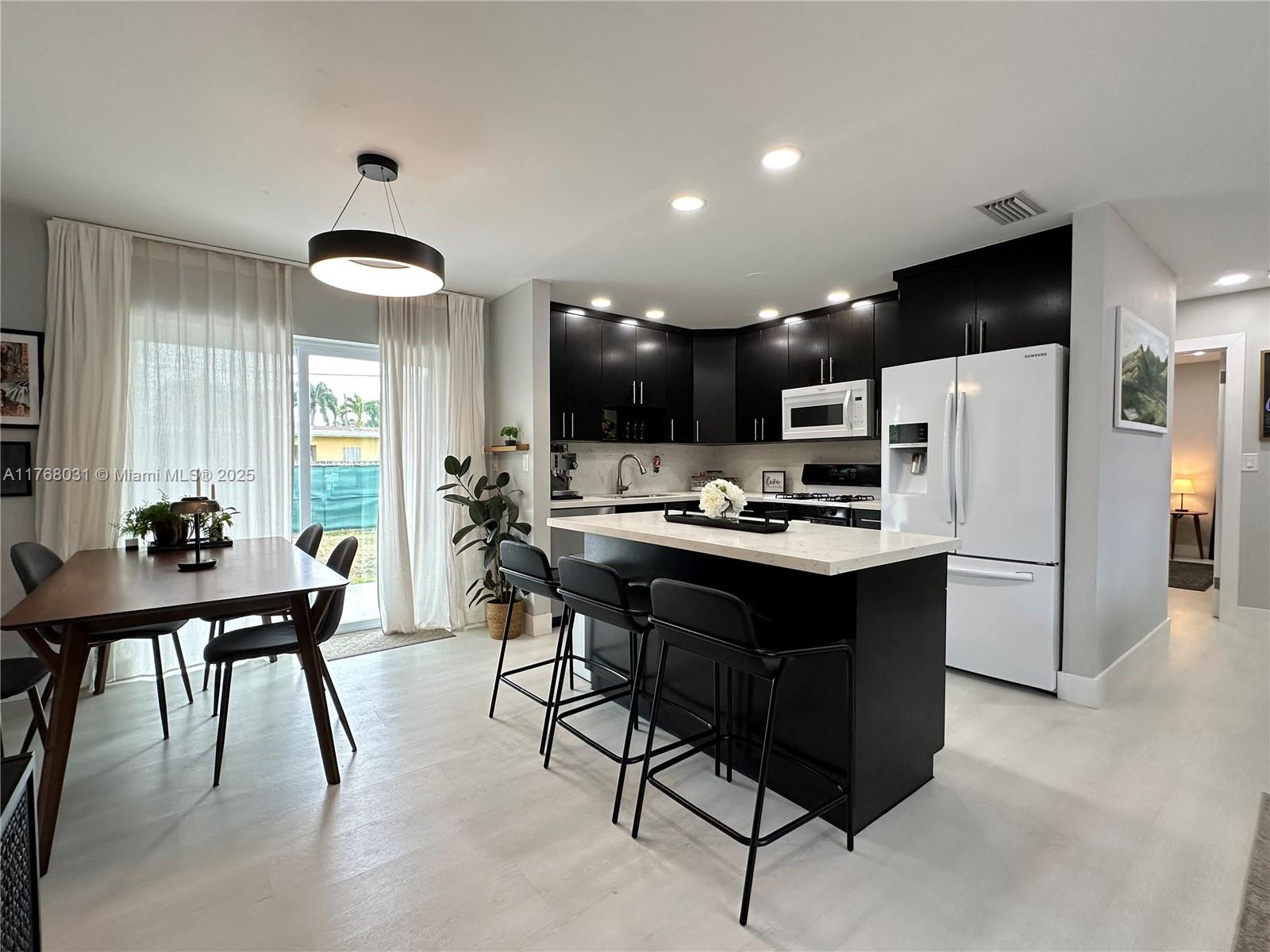 2001 North 31st Road Hollywood, FL 33021 - Photo 47 of 75 a kitchen with stainless steel appliances kitchen island granite countertop a table chairs and a refrigerator