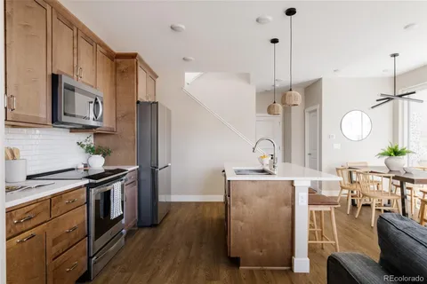 a kitchen with stainless steel appliances granite countertop a stove a sink dishwasher a refrigerator white cabinets and wooden floor