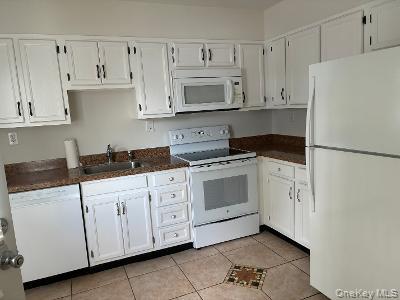 353 Woodbridge Drive Ridge, NY 11961 - Photo 5 of 11 a kitchen with white cabinets and white appliances