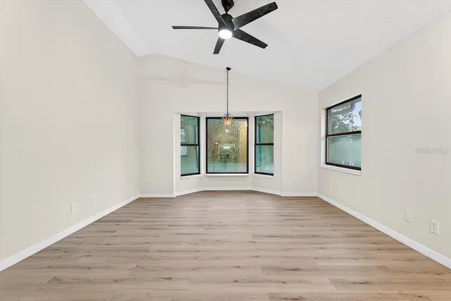 a view of an empty room with a window and wooden floor