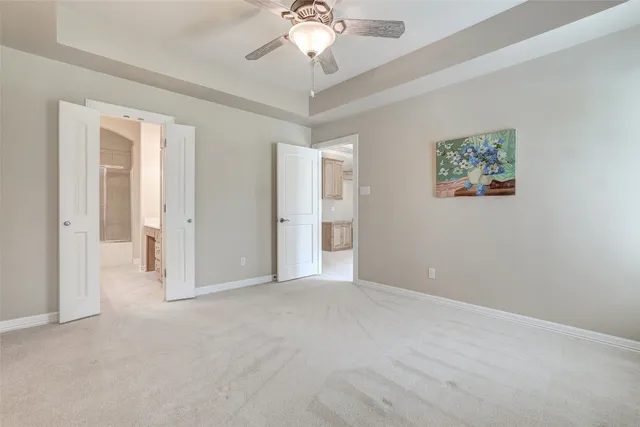 an empty room with chandelier fan and windows