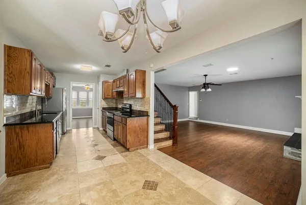 a large kitchen with stainless steel appliances kitchen island granite countertop a refrigerator a stove top oven a sink and dishwasher