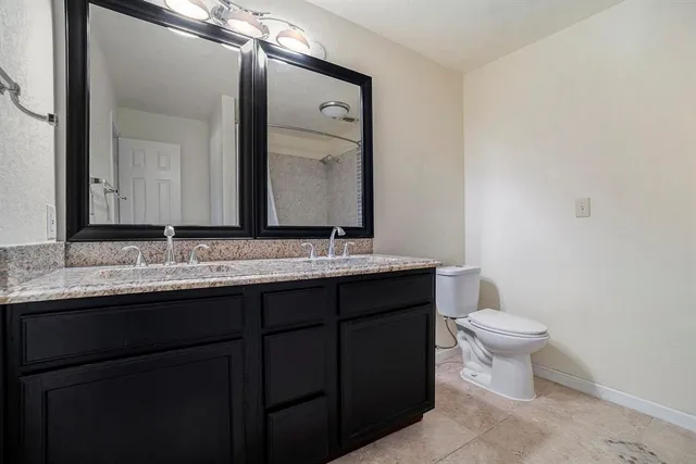 a bathroom with a granite countertop toilet a sink and a mirror