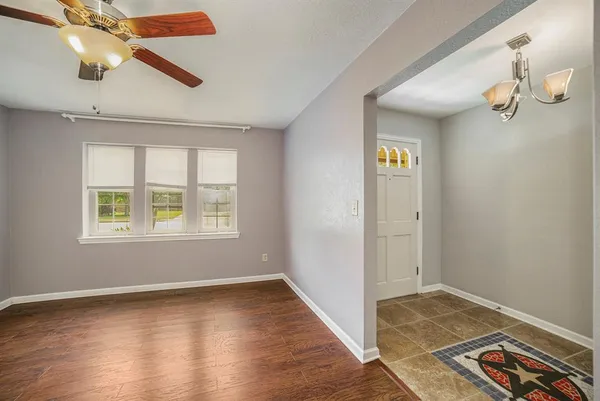 an empty room with wooden floor fan and windows