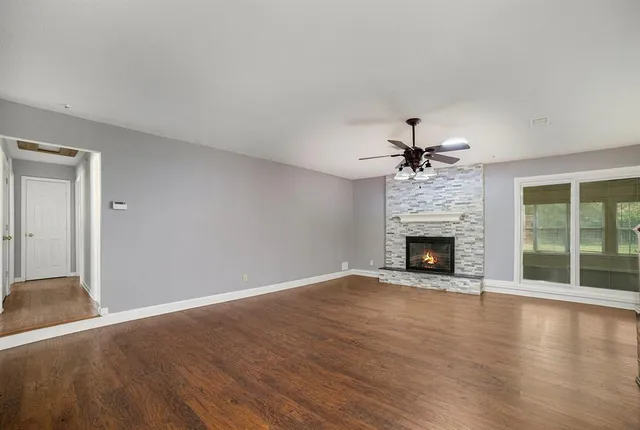 an empty room with windows fireplace and wooden floor