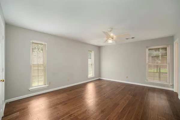 a view of an empty room with wooden floor and a window