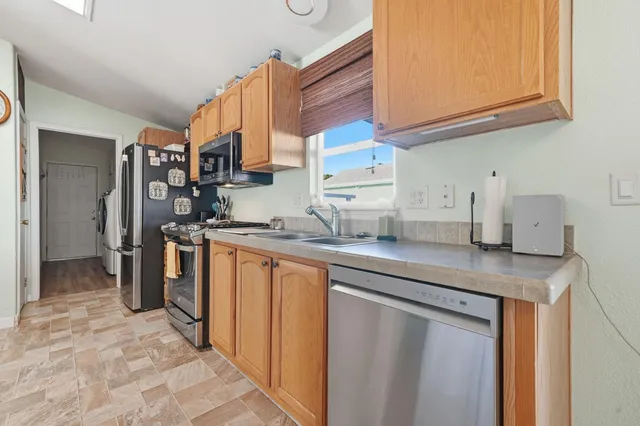 a kitchen with stainless steel appliances granite countertop a sink and a refrigerator