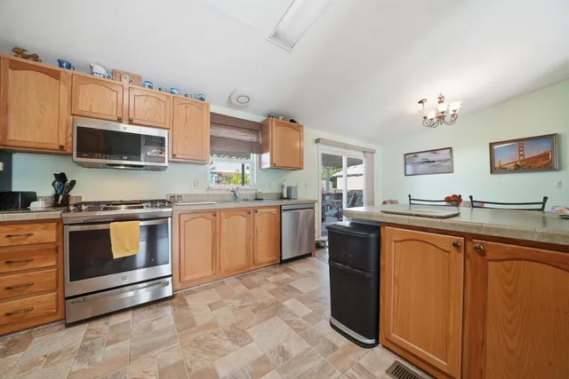 a kitchen with stainless steel appliances granite countertop a stove top oven a sink dishwasher and a microwave oven with large cabinets