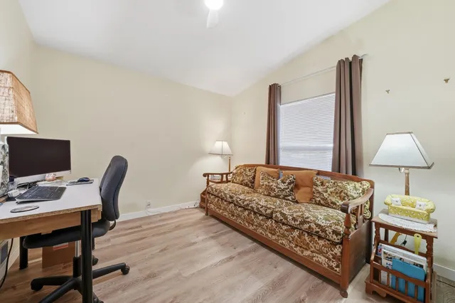 a bedroom with a bed a desk and chair with wooden floor