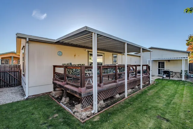 a view of a backyard with wooden deck and a garden