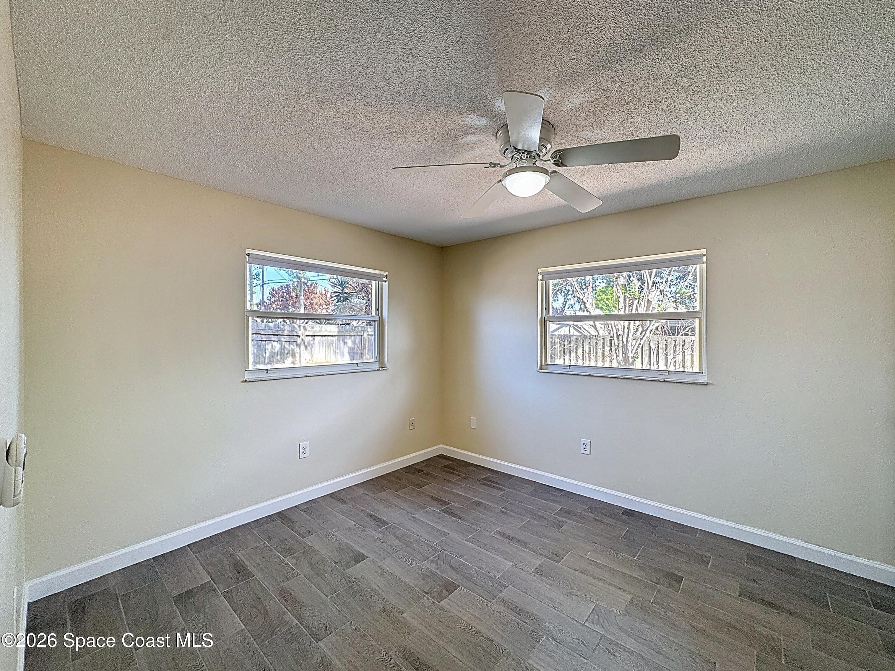 1315 Lester Court Merritt Island, FL 32952 - Photo 17 of 40 an empty room with wooden floor ceiling fan and windows