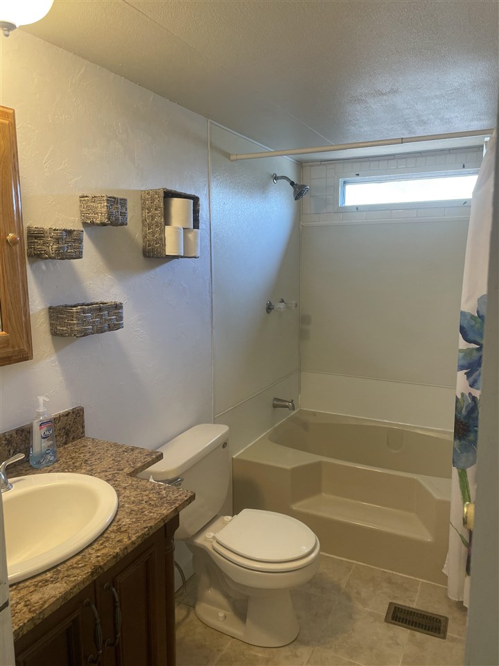3268 E Road, Unit 43 Clifton, CO 81520 - Photo 12 of 15 a bathroom with a granite countertop toilet a sink and a mirror