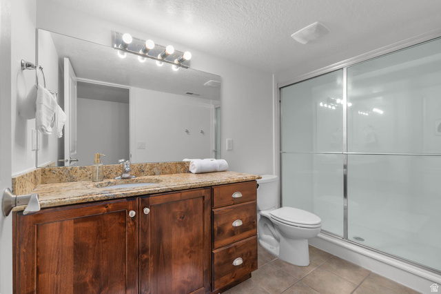 439 East 13540 South Draper, UT 84020 - Photo 32 of 46 Bathroom featuring a dark wood-finish vanity with a light-toned stone-finish countertop, undermount sink, and a mirrored wall