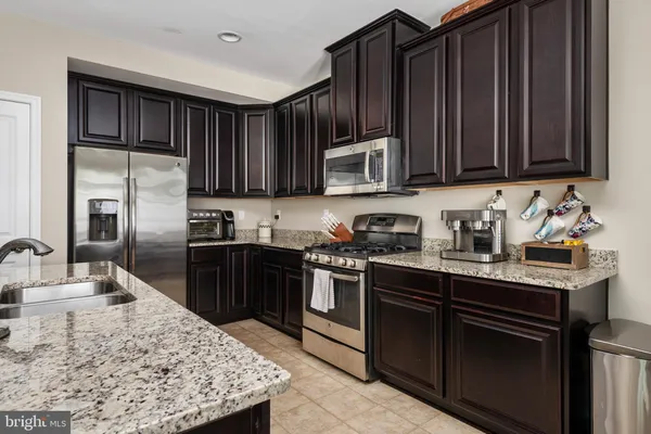 a kitchen with granite countertop wooden cabinets a stove top oven and stainless steel appliances